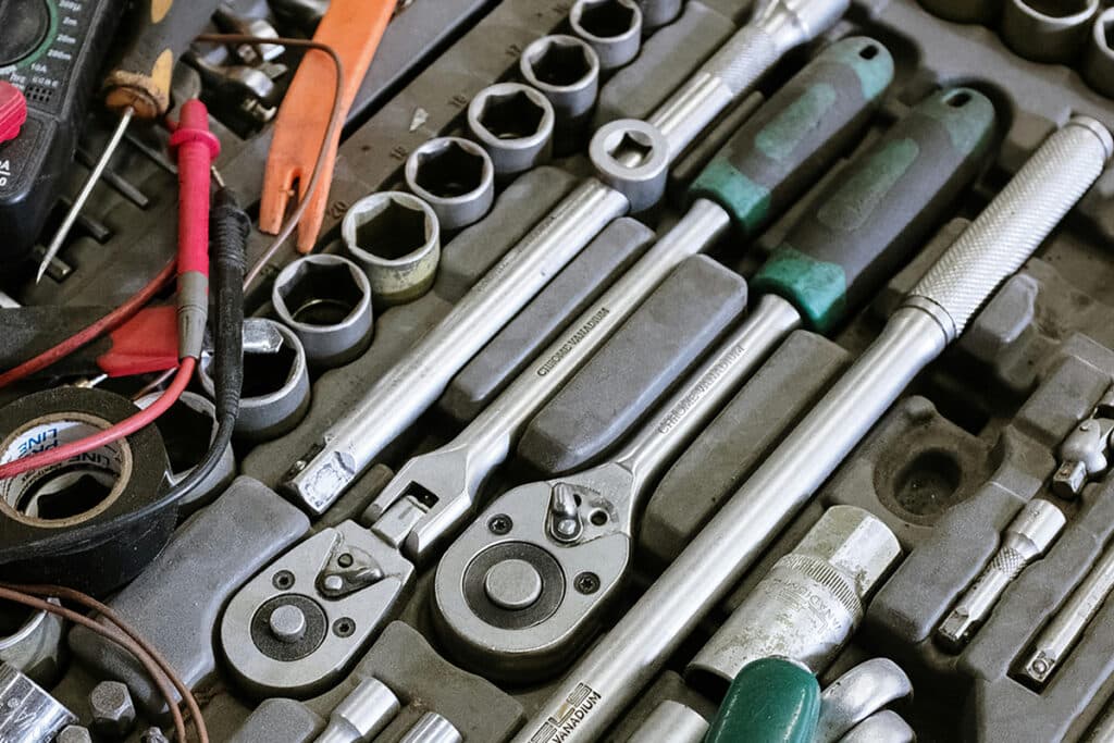 An assortment of HVAC service tools, including wrenches, sockets, and a multimeter, neatly arranged in a toolbox.
